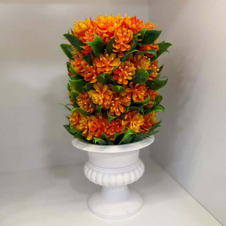 Decorative topiary with orange flowers and green leaves in a white urn on a light background