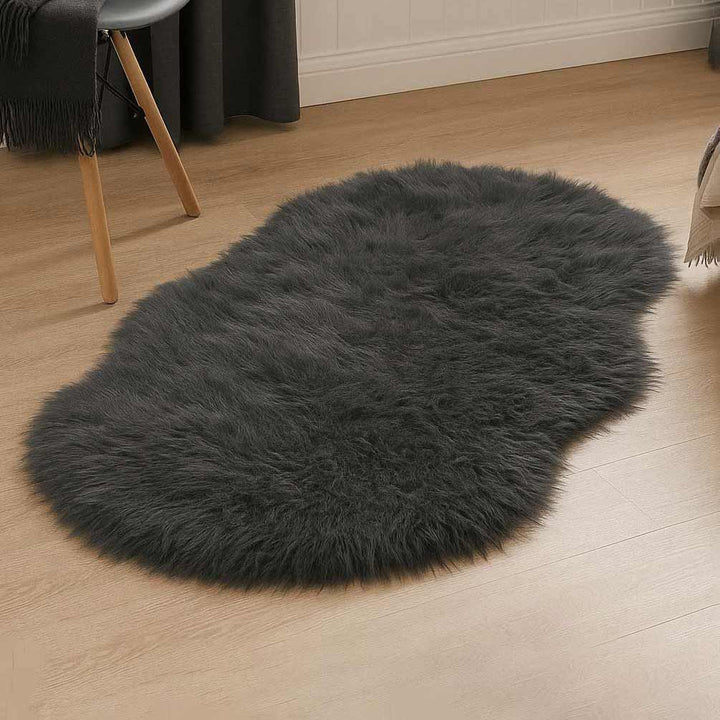 Dark gray fluffy rug on a wooden floor with a chair and black curtain in the background.