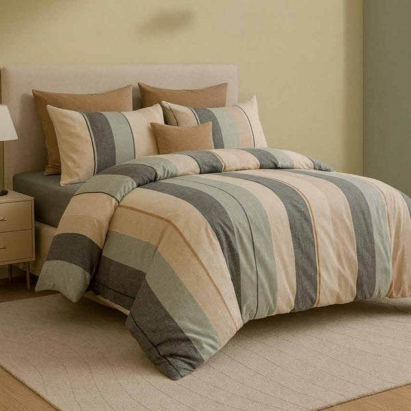 Striped bedding set on a bed with matching pillows against a beige wall.
