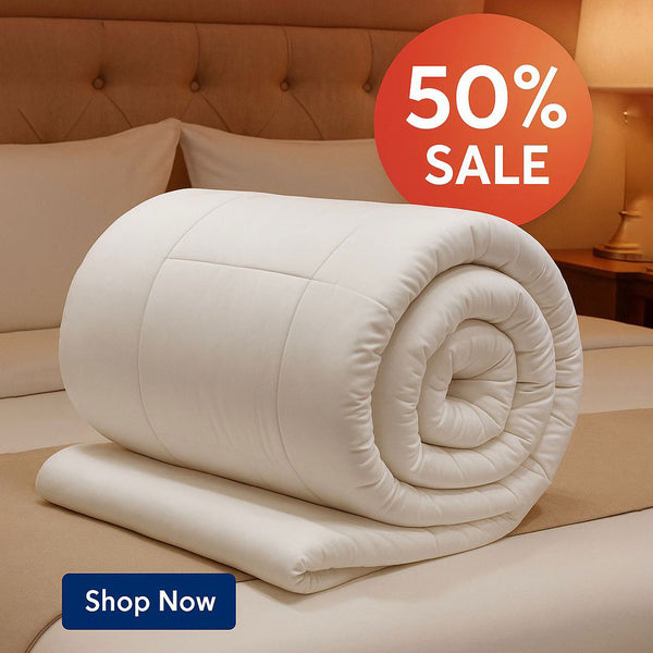 Rolled-up white quilt on a bed with a '50% Sale' and 'Shop Now' labels