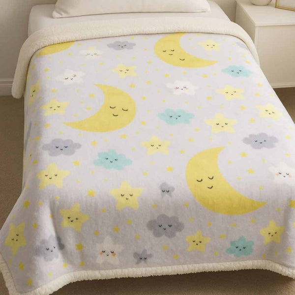 Children's blanket with moon, star, and cloud pattern on a bed.