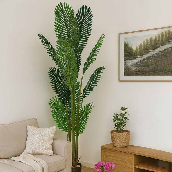 Living room with a large artificial palm plant, beige sofa, and framed picture on the wall.