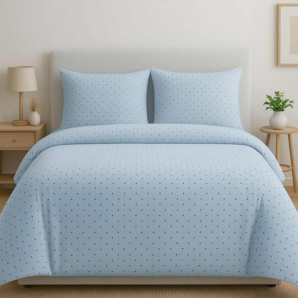 Light blue polka dot bedding set on a bed in a bedroom setting.