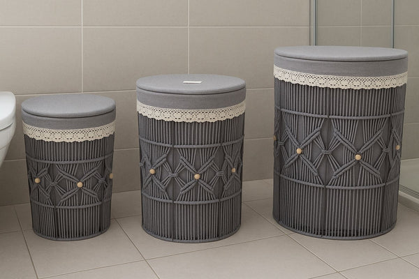 Three gray laundry baskets with lace trim on a tiled bathroom floor.