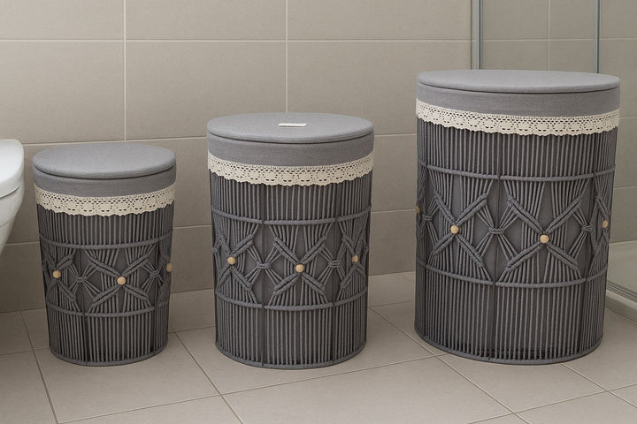 Three gray laundry baskets with lace trim on a tiled bathroom floor.