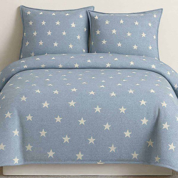 Blue star-patterned bedding set on a bed with white background