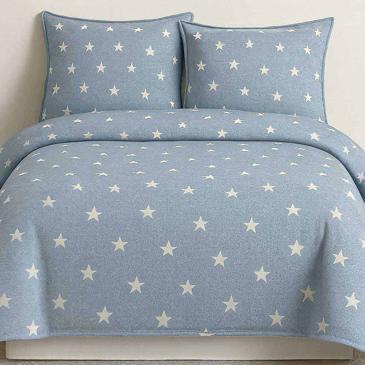 Blue star-patterned bedding set on a bed with white background