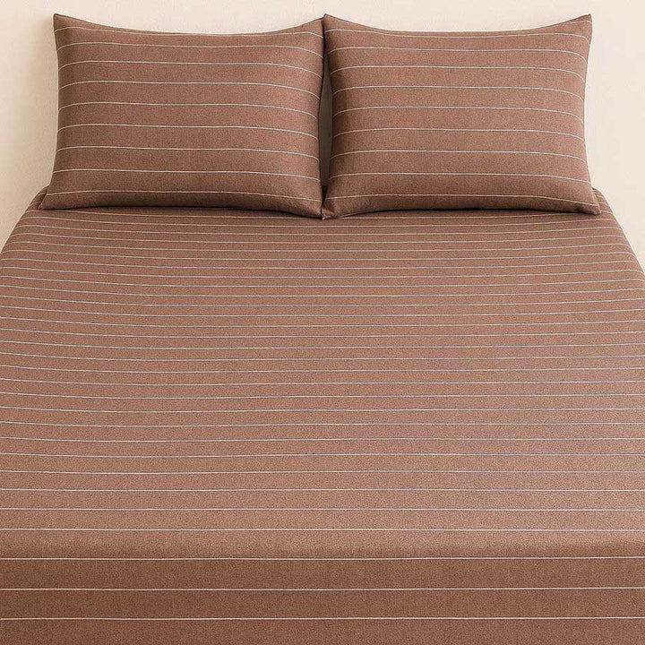 Brown striped bed sheet set with matching pillows on a beige background
