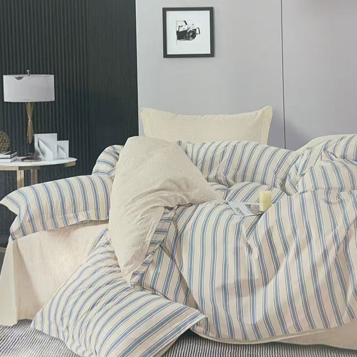 Striped bedding with beige pillows on a bed in a bedroom setting.