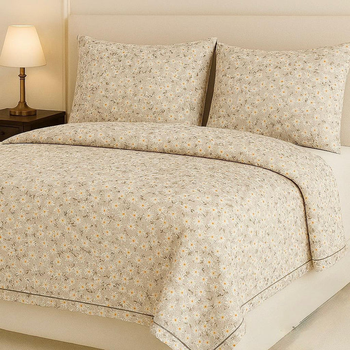 Floral patterned bedspread on a bed with matching pillows, nightstand, and lamp.