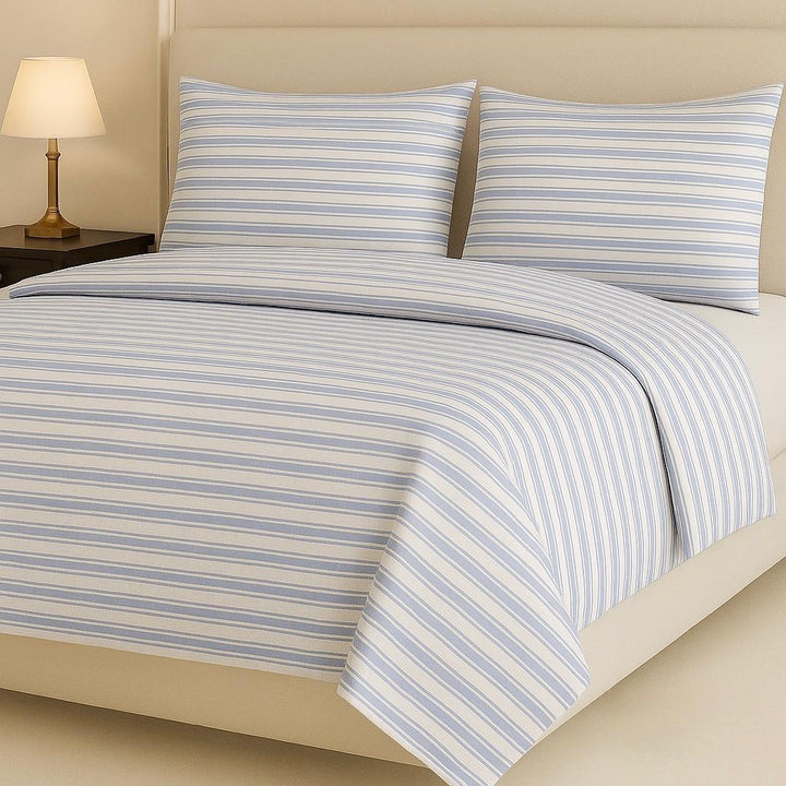 Striped bedding set on a bed with a lamp in the background