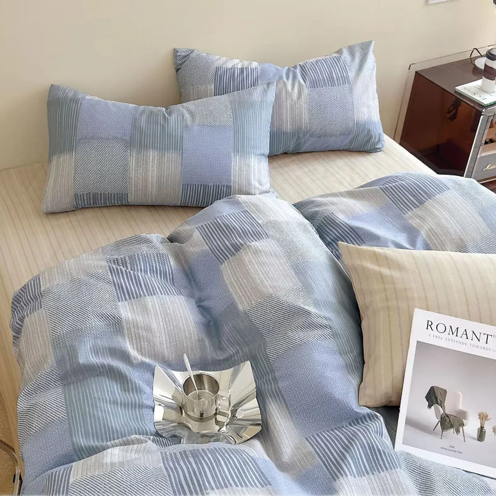 Blue and gray checkered bedding set on a bed with a magazine.