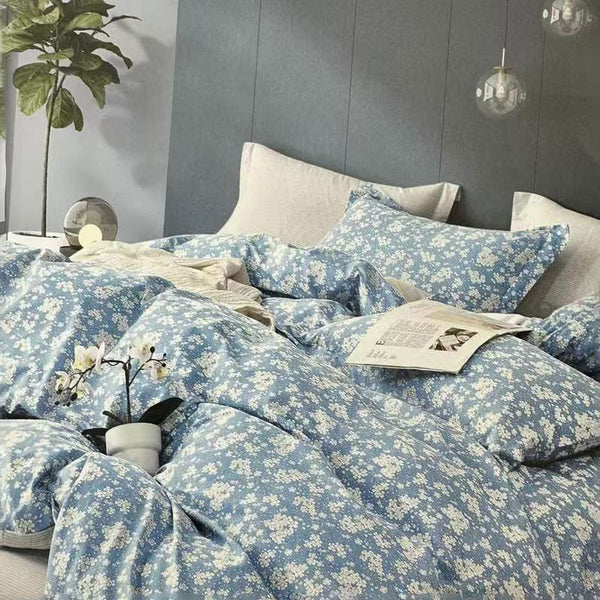 Blue floral bedding set on a bed with a gray headboard and decorative elements.