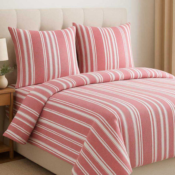 Pink and white striped bedding set on a bed in a bedroom.
