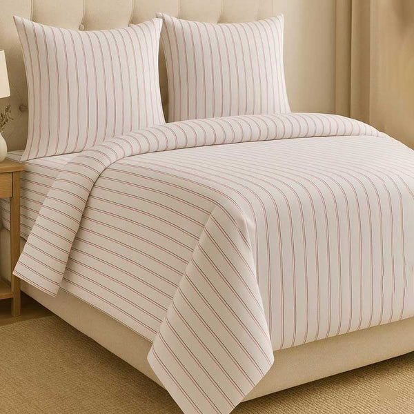Striped bedding set on a bed with a beige headboard.