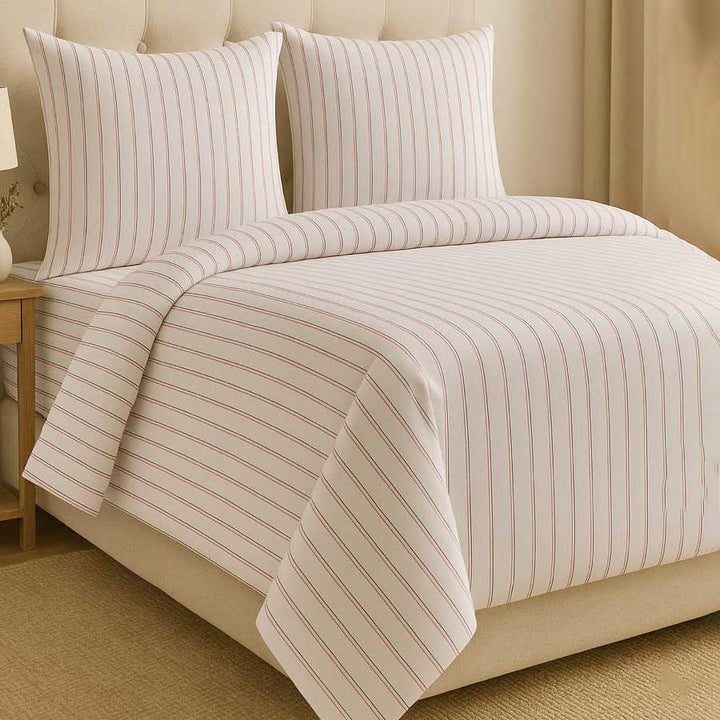 Striped bedding set on a bed with a beige headboard.