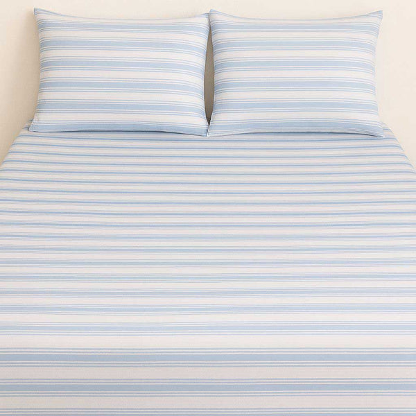 Striped bed sheet set with two pillows on a beige background