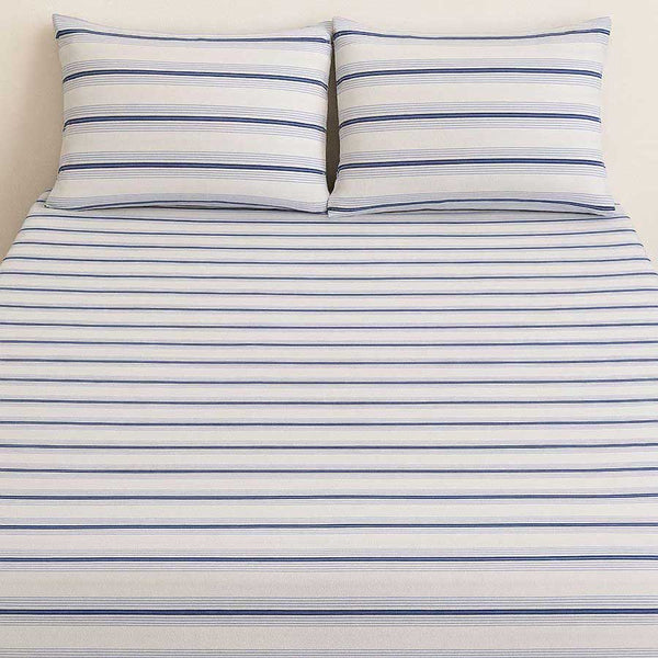 Striped bed sheet set with two pillows on a plain background