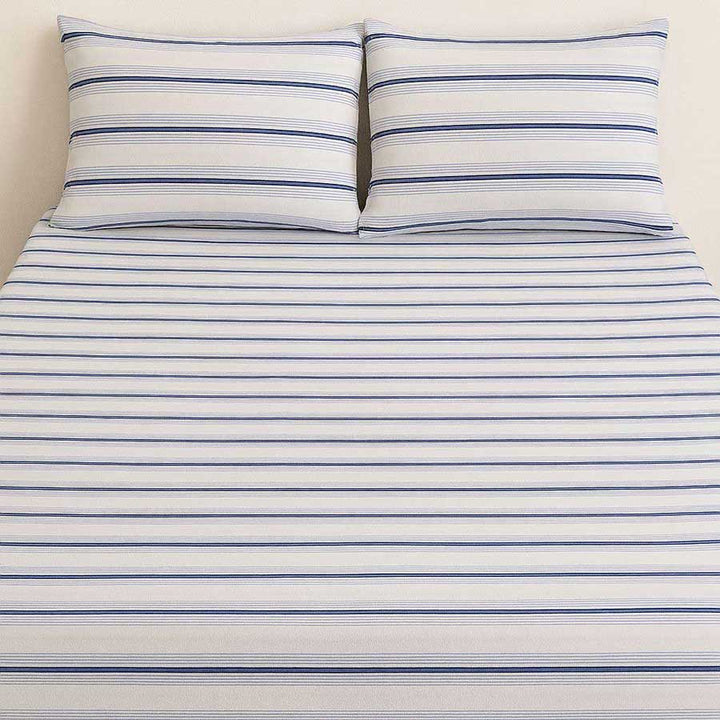 Striped bed sheet set with two pillows on a plain background