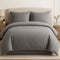 Gray bedding set on a bed in a bedroom setting