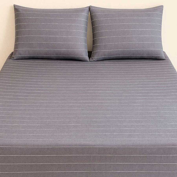 Gray striped bed sheet set with two matching pillows on a plain background