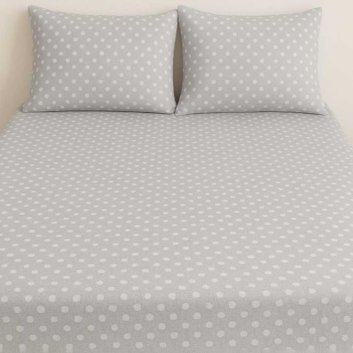 Gray polka dot bedding set with two pillows on a bed.