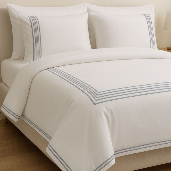 White bed set with gray stripes on a bed in a bedroom setting