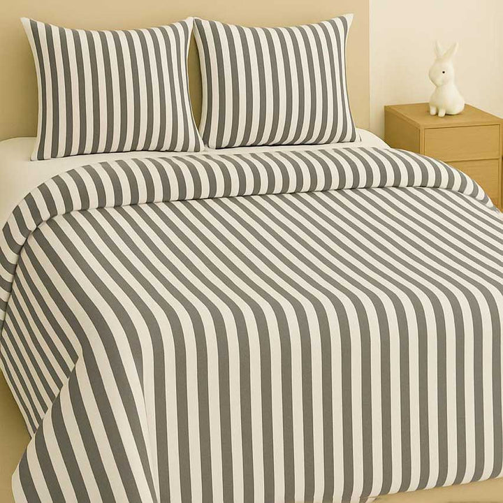 Striped bedspread with matching pillows on a bed in a bedroom setting.