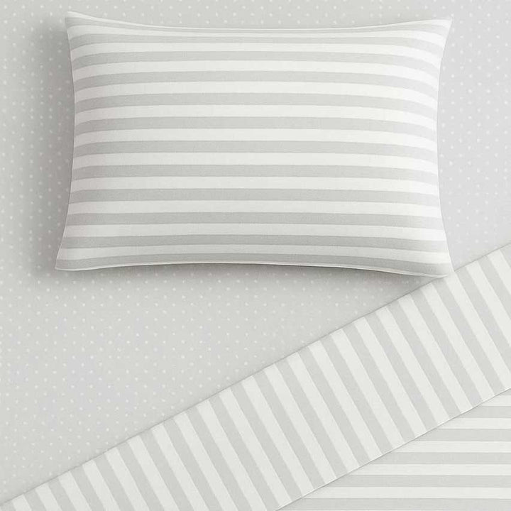 Striped pillowcase on a matching bed sheet with a polka dot pattern