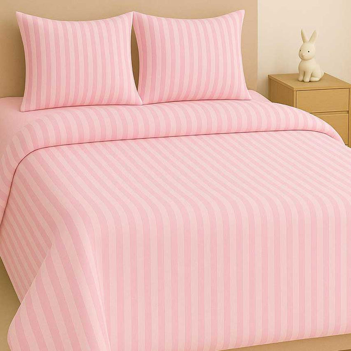 Pink striped bedding set on a bed with a nightstand and decorative item in the background.