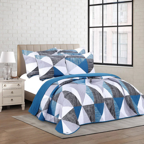 Geometric patterned bedspread set on a bed in a bedroom with a lamp and nightstand.