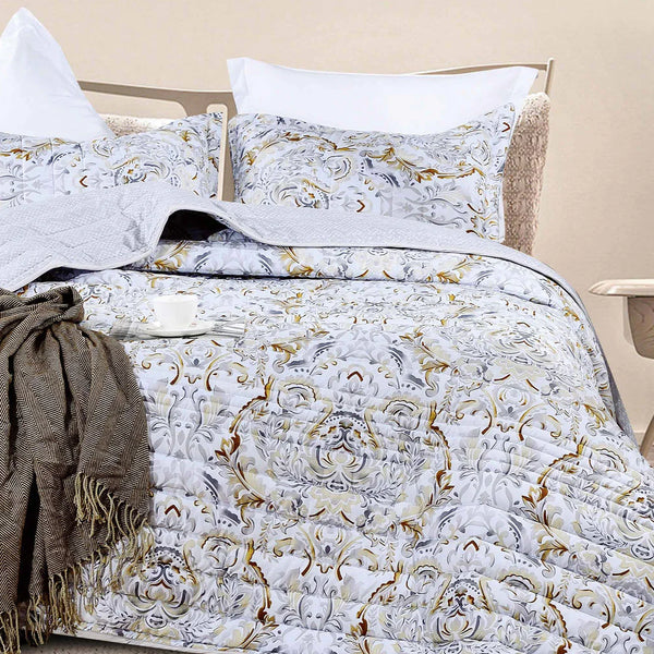 Decorative bedspread set with intricate patterns on a bed in a bedroom setting.