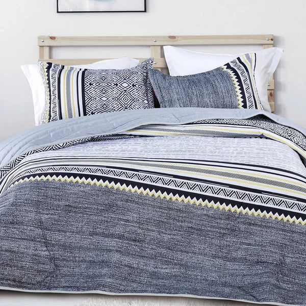 Gray striped bedspread set on a bed with white pillows.