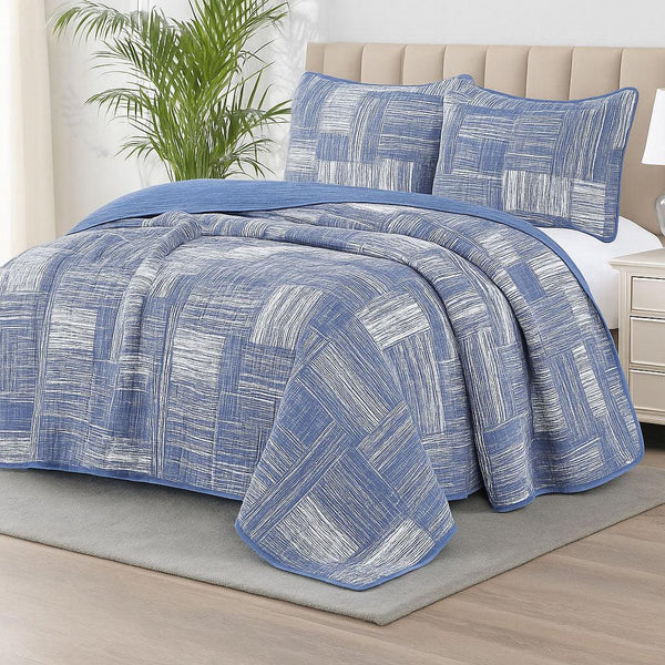 Blue and white patterned bedspread set on a bed in a bedroom setting.