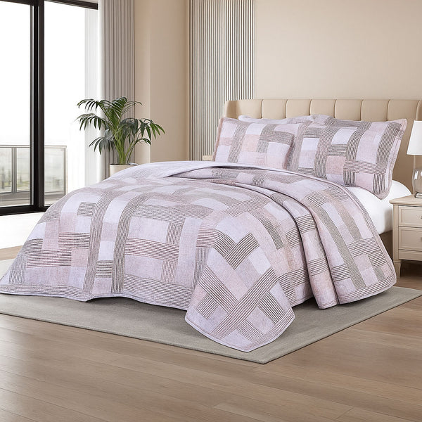 Summer bedspread with a soft geometric weave pattern in blush and taupe tones, styled on a bed with matching shams in a modern bedroom with large windows