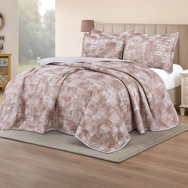 Summer bedspread with a crosshatch square pattern in earthy beige tones, styled with matching shams in a softly lit bedroom