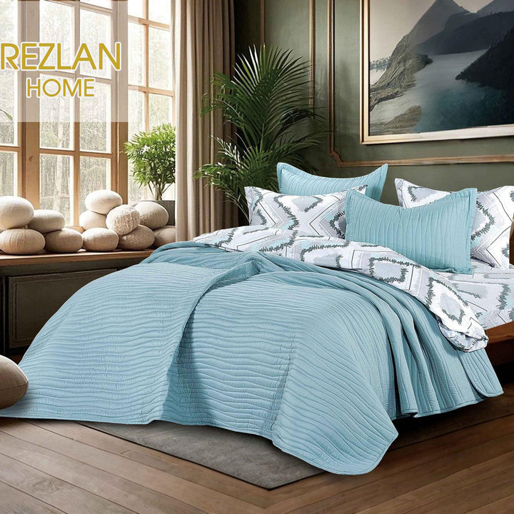 Summer pale blue bedspread set with quilted wavy lines pattern, styled on a made bed
