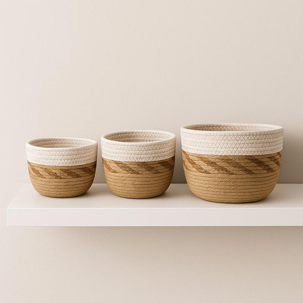 Three woven baskets with wooden and white accents on a white shelf against a beige wall.