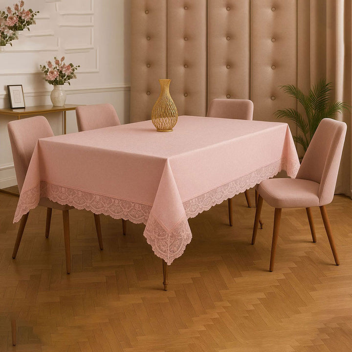 Dining room with a table covered by a pink lace tablecloth, surrounded by chairs.