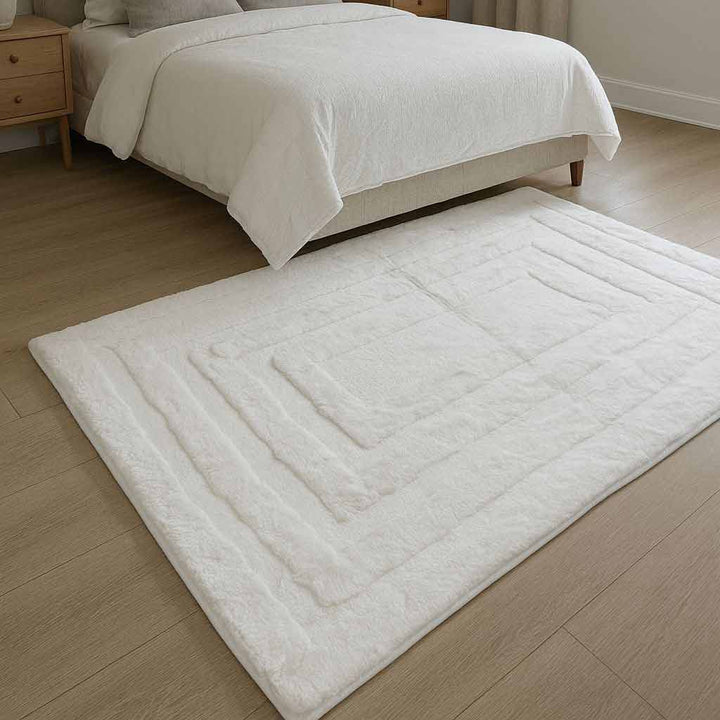 White bath mat on a wooden floor in a bedroom setting