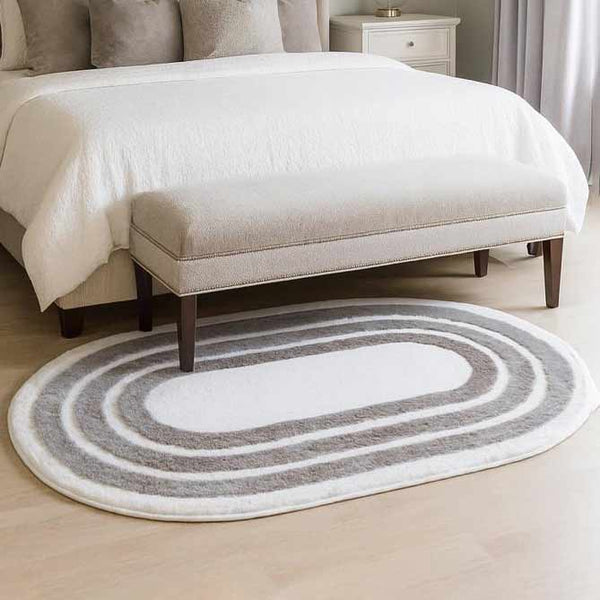 Oval-shaped rug with concentric circles on a light wood floor in a bedroom setting.