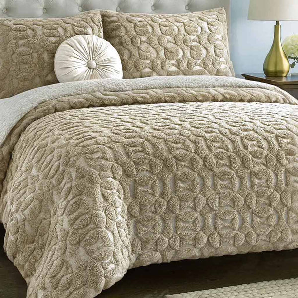 Beige textured quilted duvet cover set on a bed with matching pillows and a lamp in the background.