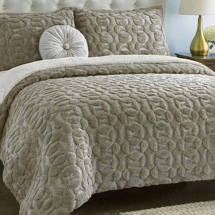Textured beige duvet cover set on a bed with matching pillows and a lamp in the background.