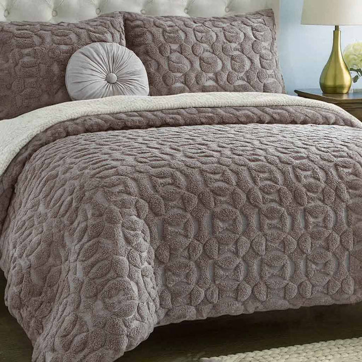 Textured quilted duvet cover set on a bed with matching pillows and a lamp in the background.