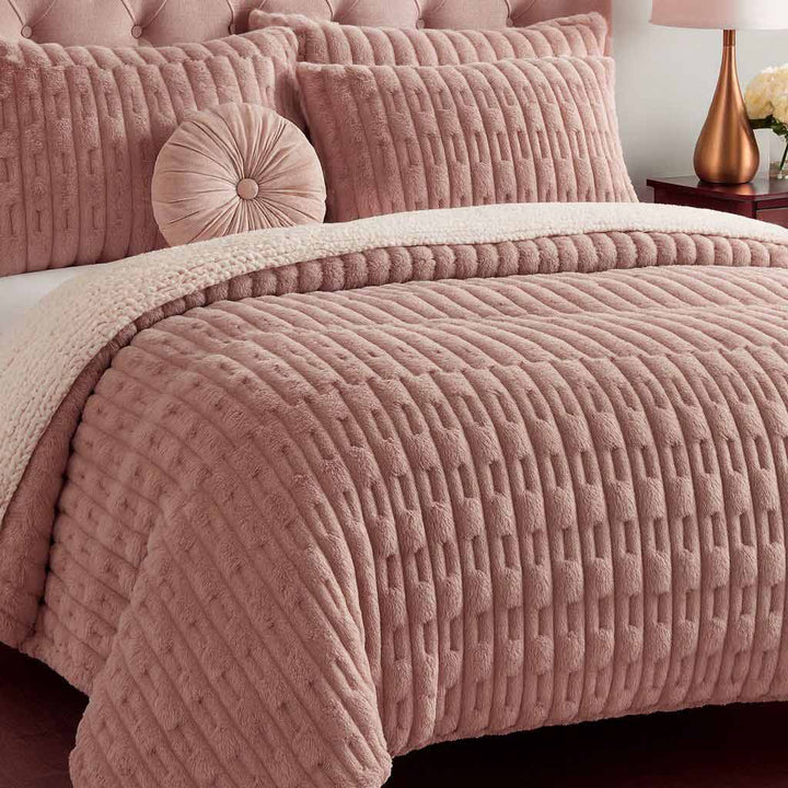 Pink textured bedding set on a bed with matching pillows in a bedroom setting.