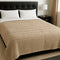 Beige qblanket uilt on a bed with a black headboard and nightstand in a bedroom setting.