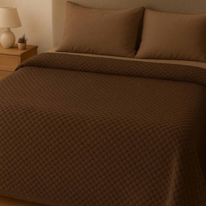 Brown checkered blanket on a bed in a bedroom setting