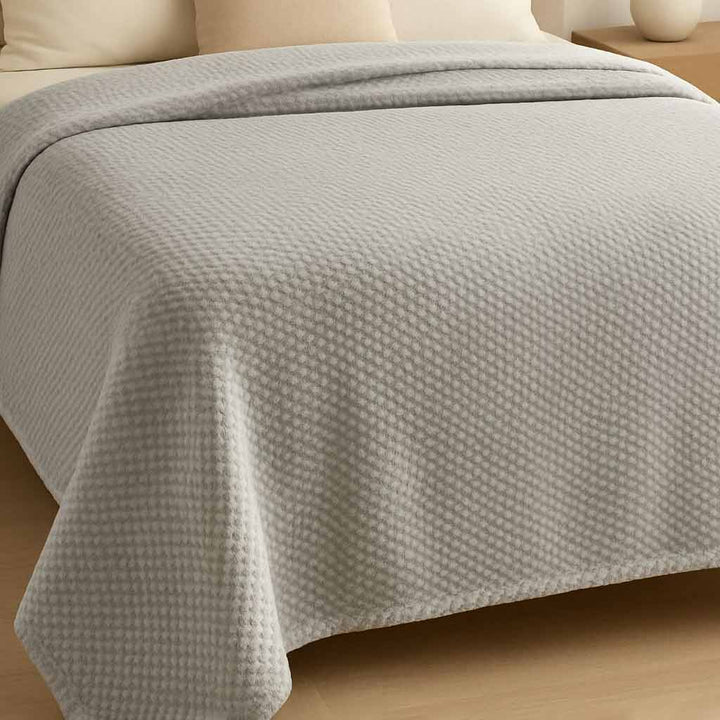 Gray textured blanket on a bed in a bedroom setting