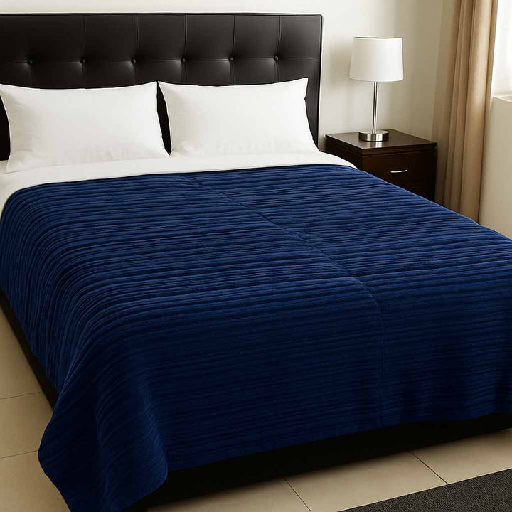 Bed with a navy blue blanket and white pillows in a bedroom setting.